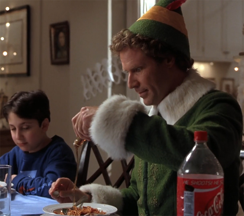 Buddy the elf pours maple syrup onto his spaghetti